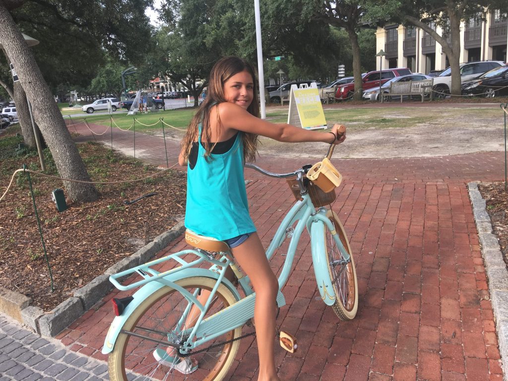 A girl riding a bike in the center of Rosemary Beach on 30A.